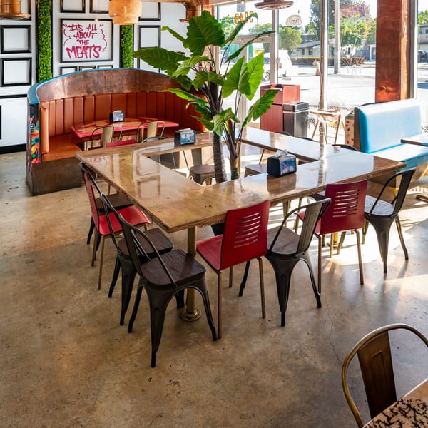 The Better Taco restaurant interior with a large U-shaped table, red and black chairs, and booth seating.
