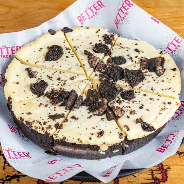 Oreo cheesecake, sliced into wedges, on The Better Taco branded parchment paper.